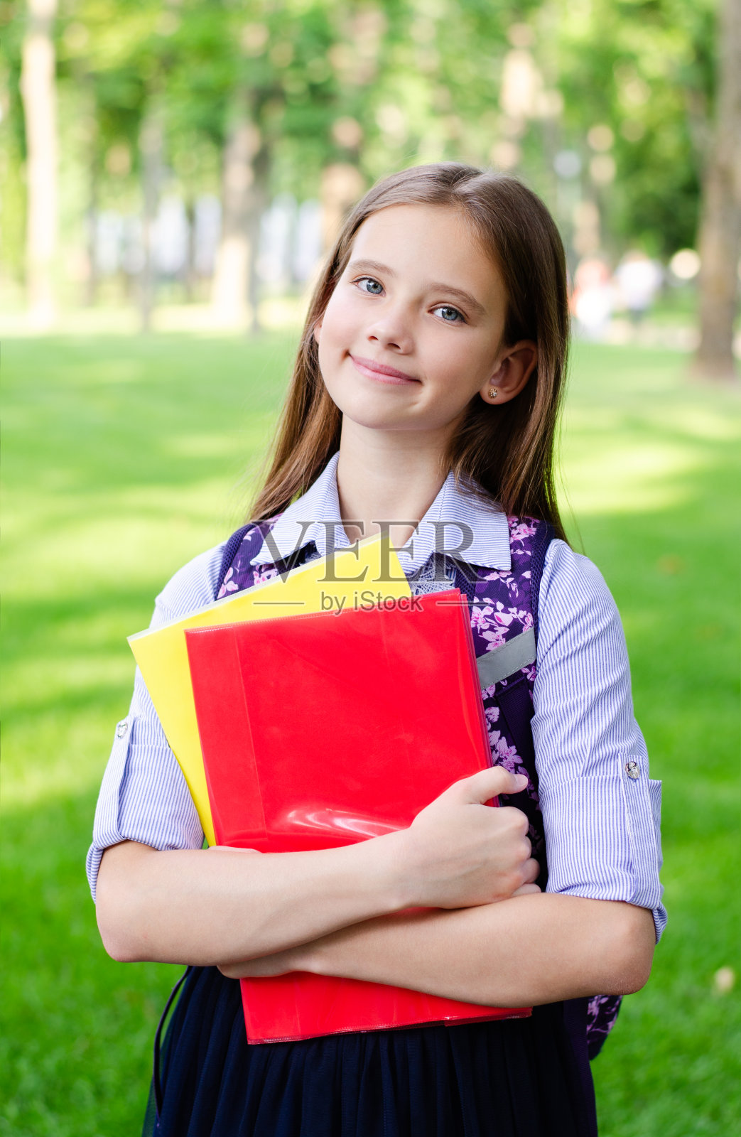回到学校。教育的概念。可爱的微笑的女学生拿着书在户外照片摄影图片