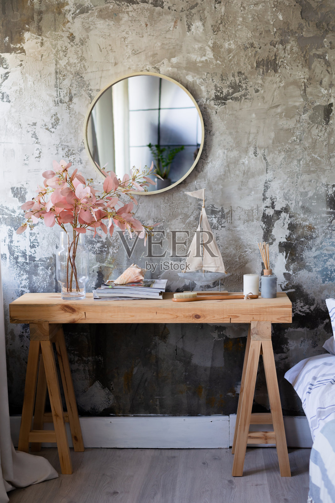 一张现代的木桌、一面圆镜子、鲜花和房子的配件，背景墙上还有一幅画室风格的复制品。放荡不羁的风格照片摄影图片
