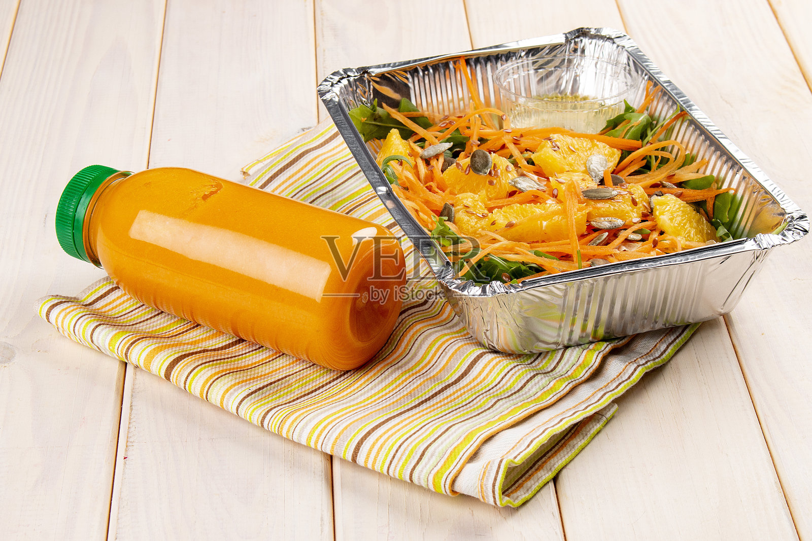 在白色的背景上，装有橘子、南瓜籽和新鲜果汁的沙拉。外卖。饮食和健康食品。照片摄影图片