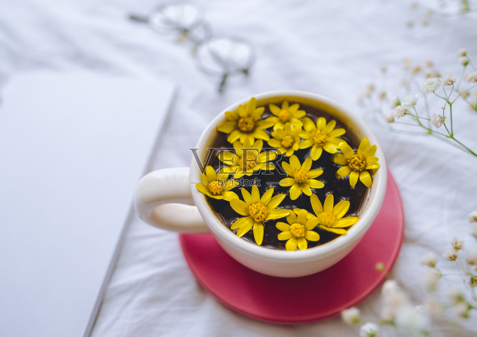白色床上放着黄花的杯子照片摄影图片