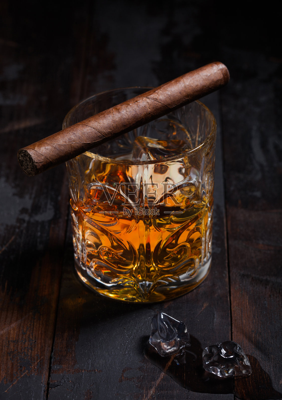 单一麦芽苏格兰威士忌在水晶玻璃杯与冰块和古巴雪茄在木制背景照片摄影图片