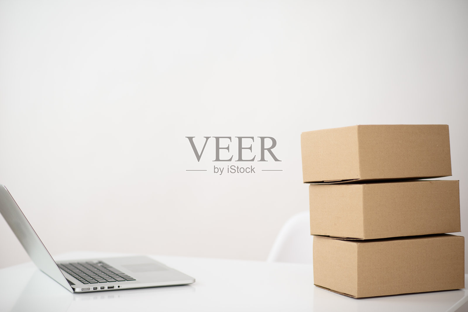 一张桌子的照片，上面有一台笔记本电脑和一堆纸板箱，每边都有空闲的文字空间照片摄影图片