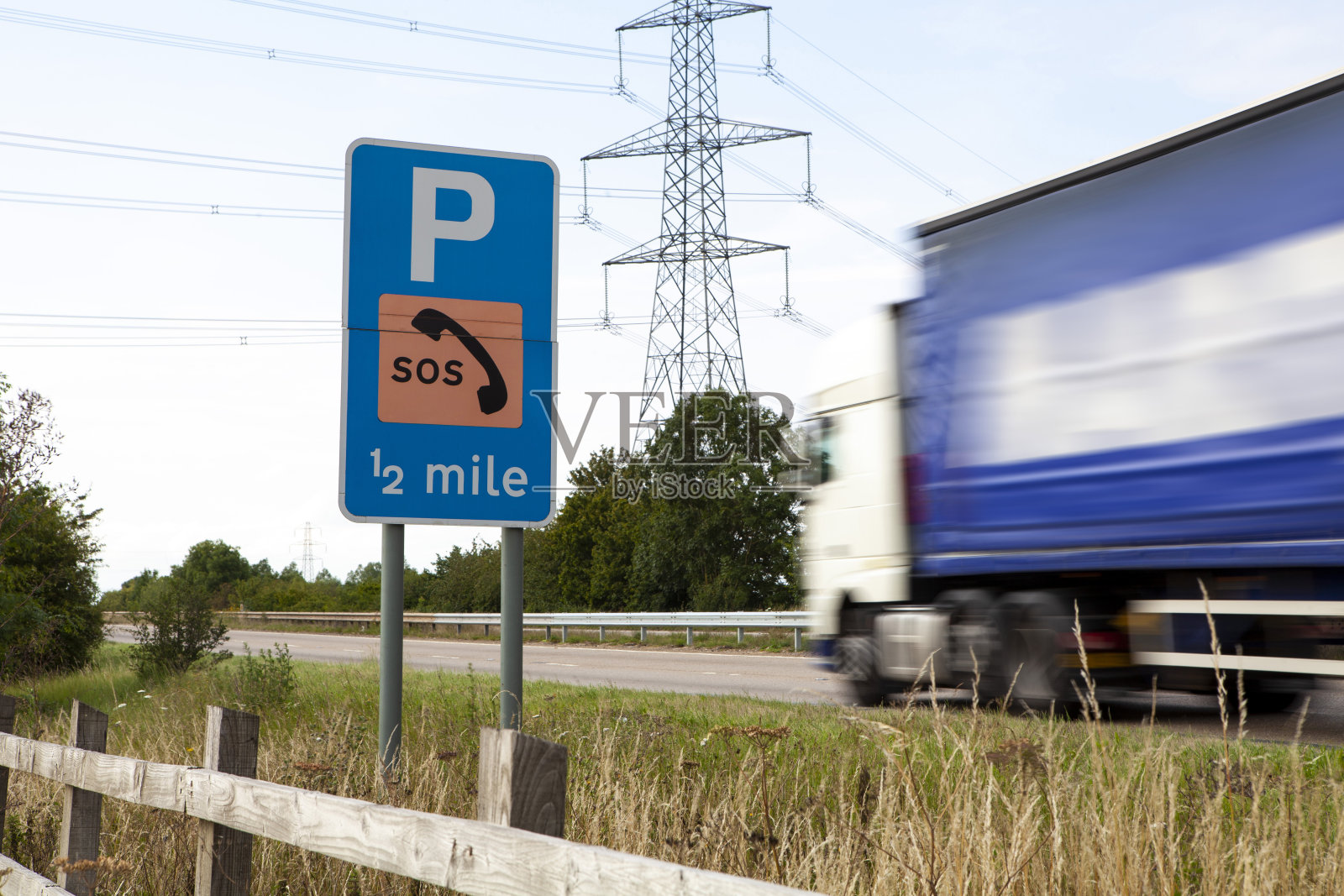 卡车在双车道上的运动模糊通过一个路标和电塔照片摄影图片