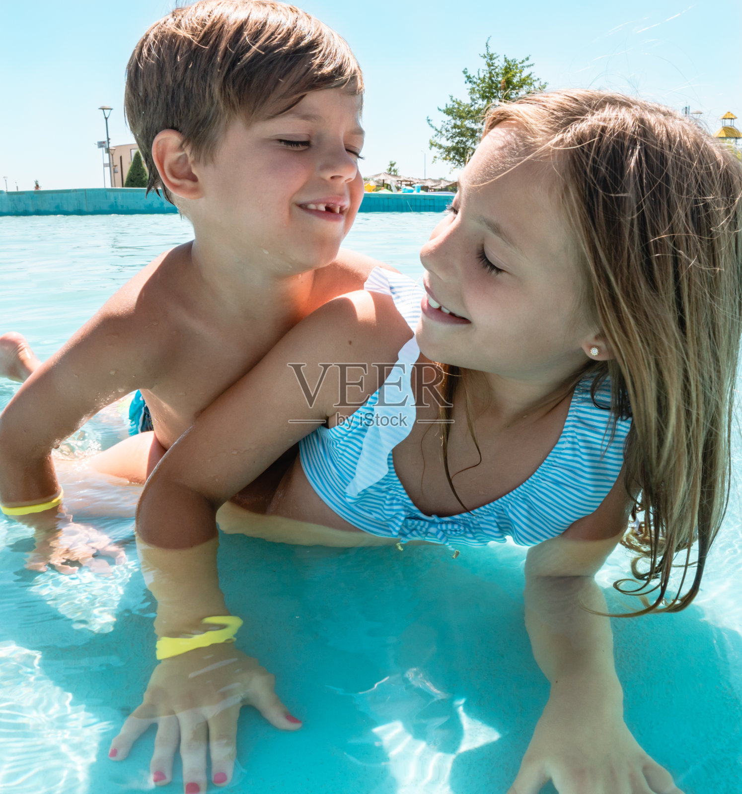 兄弟姐妹在泳池里玩耍照片摄影图片