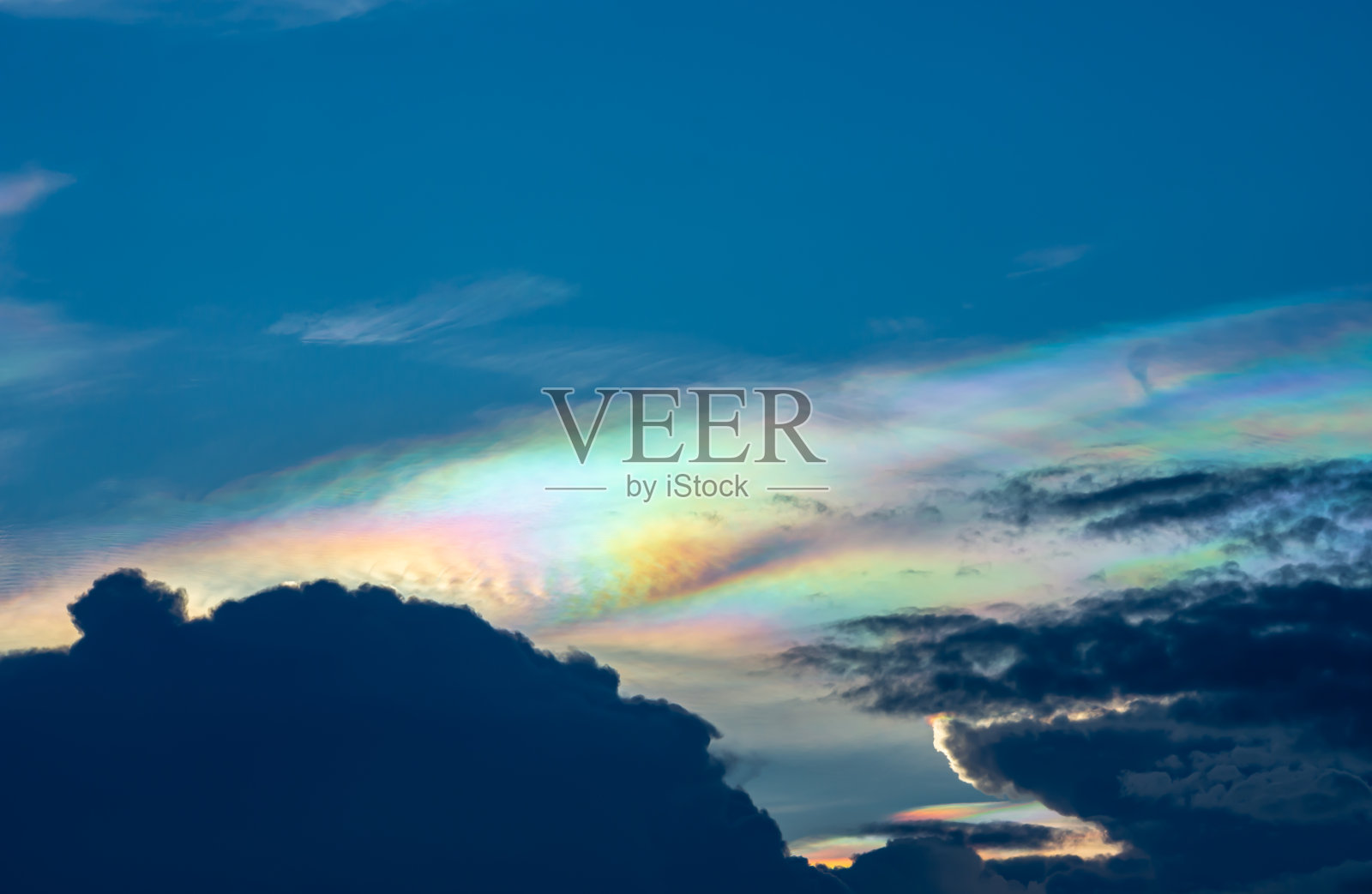 美丽的彩虹云在晚上的乌云之上。照片摄影图片