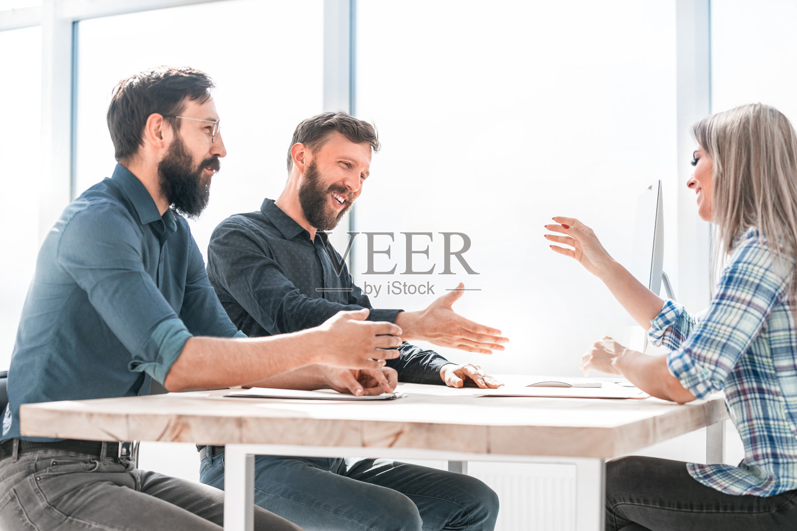 商务人士坐在办公室的桌子上讨论一些事情照片摄影图片