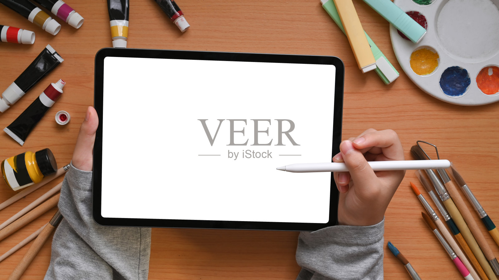 上面的创意设计师的手拿着一个白色的空白屏幕平板电脑。照片摄影图片