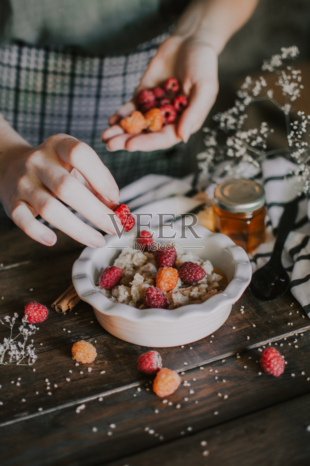 美味健康的早餐，有树莓和蜂蜜。早餐燕麦片。晨光美学和美丽的木桌布局。照片摄影图片