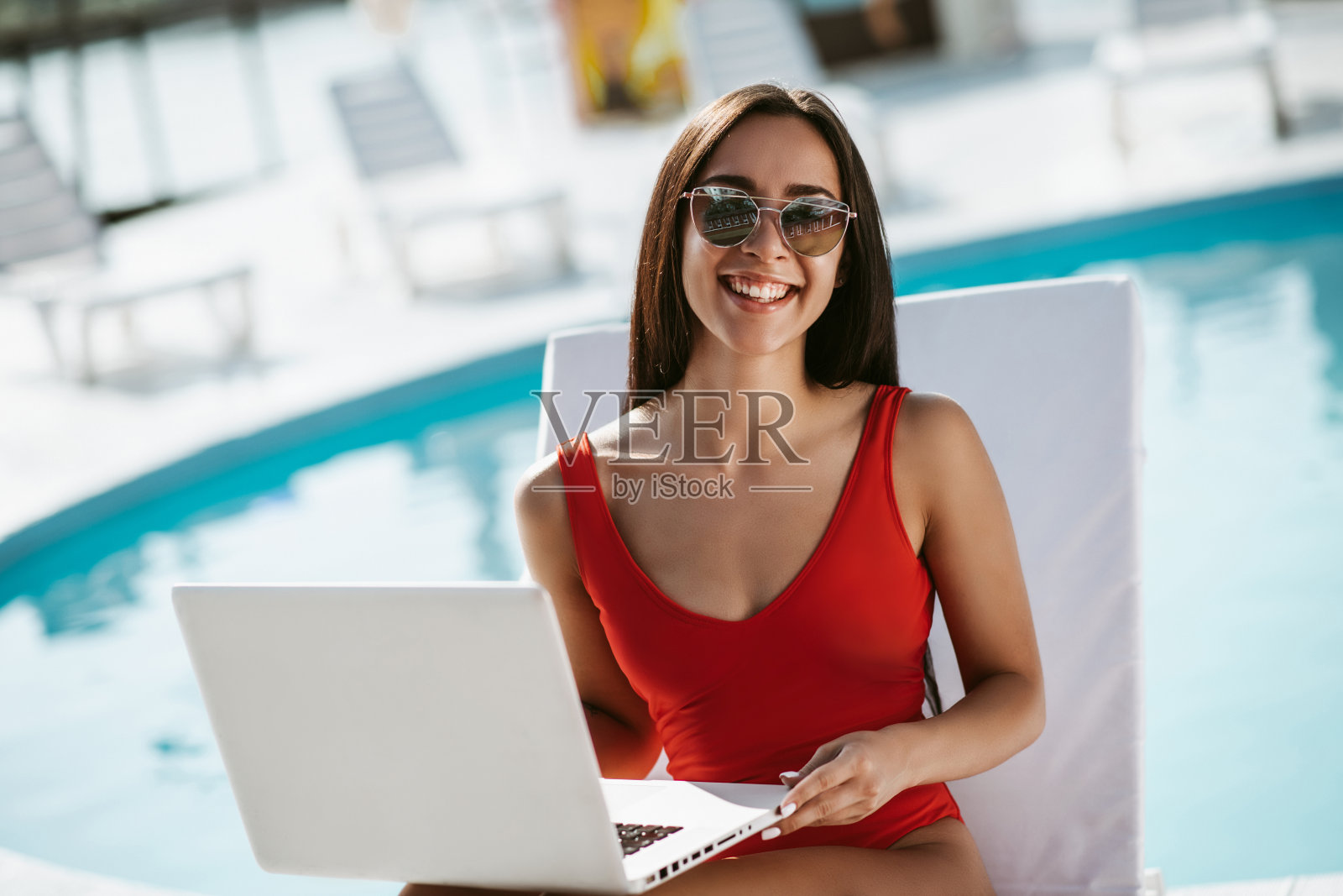 穿着泳衣，戴着墨镜，躺在日光浴床上的女人照片摄影图片