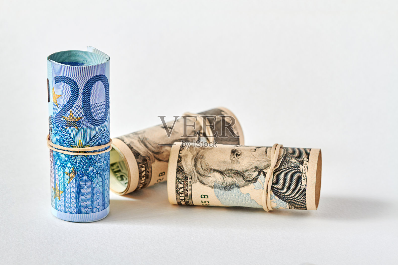 二十欧元纸币卷成小管，站在二十美元纸币的背景上。欧元优于美元的概念。特写镜头,有选择性的重点照片摄影图片