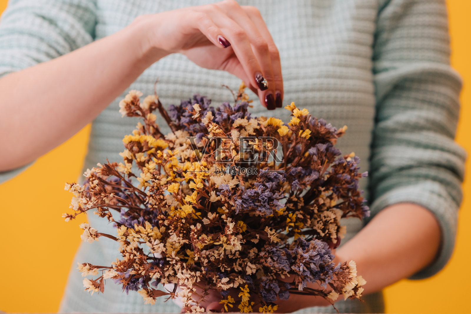 干野花。白色花瓶里插着许多蓝色和黄色的小花。花店女孩调整花束。照片摄影图片