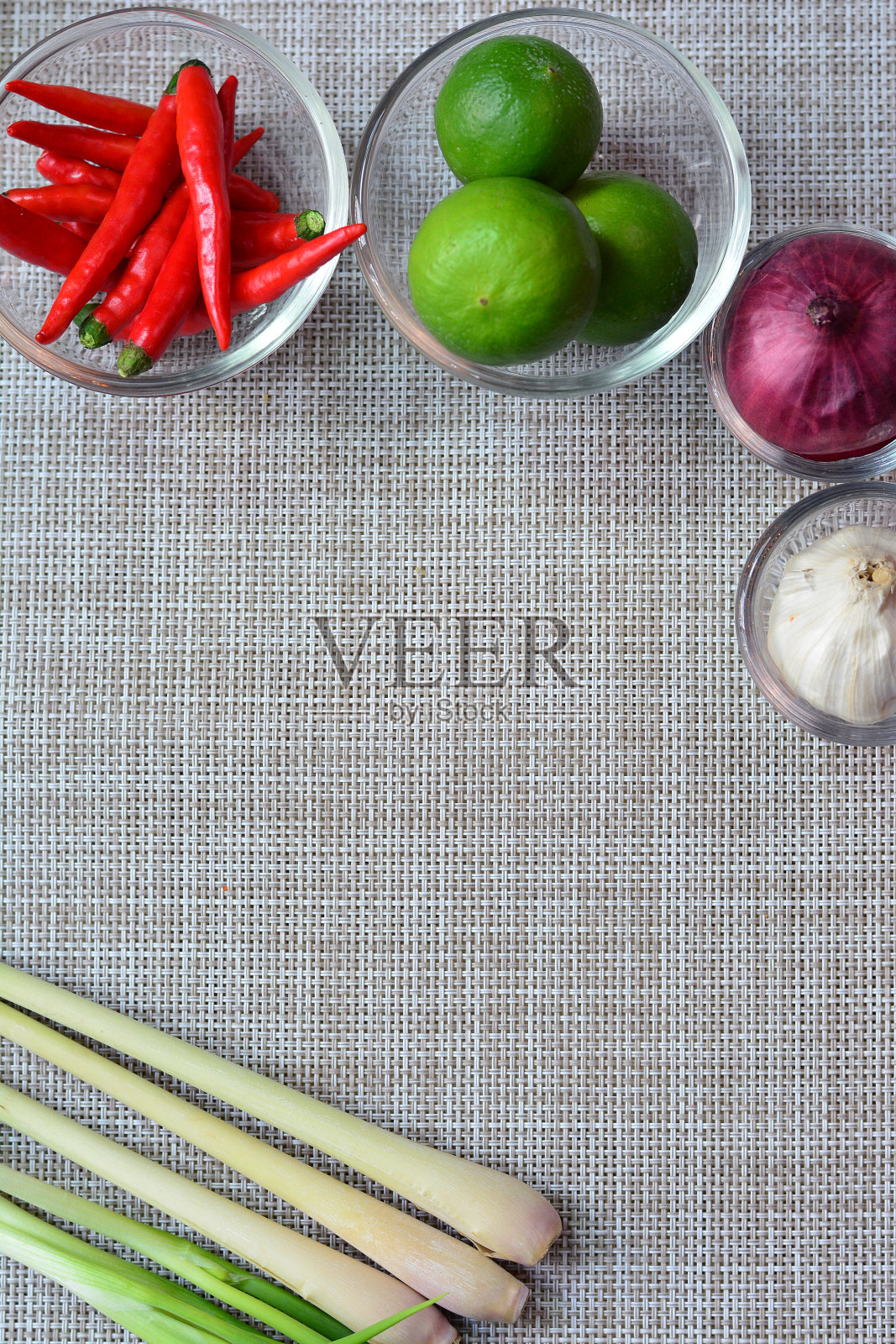 灰色的餐垫纹理以辣椒、柠檬、洋葱、大蒜和柠檬草为背景照片摄影图片