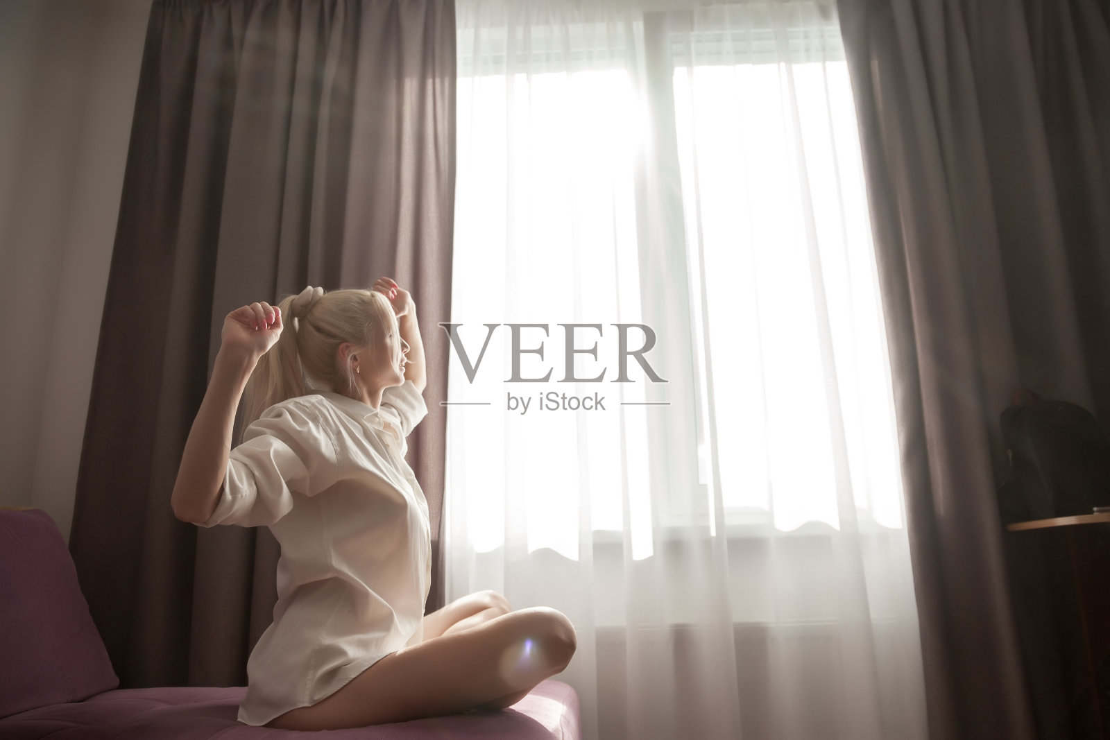 女孩坐在房子窗户的沙发上看着窗外的阳光照片摄影图片