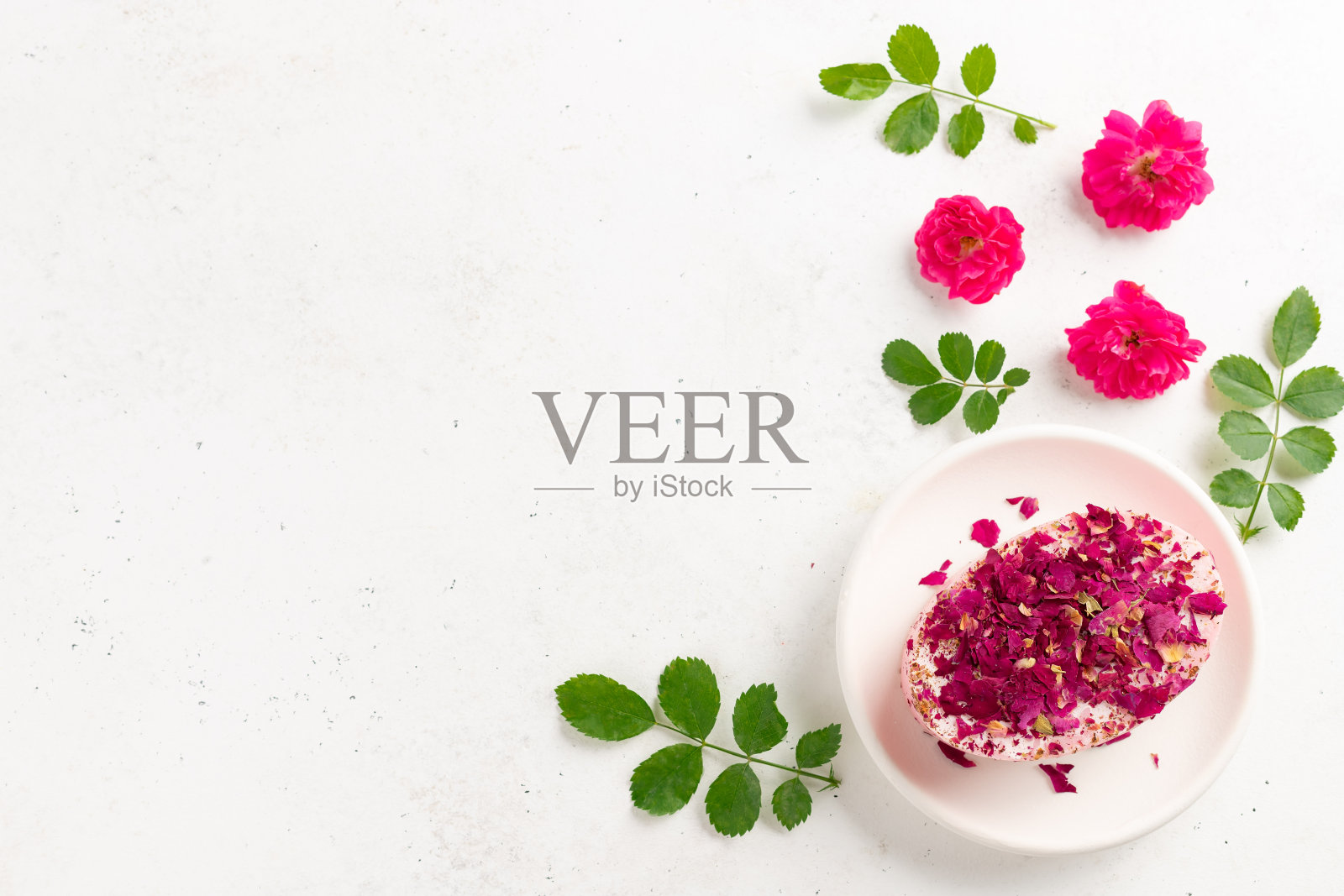 有机香皂与干玫瑰，新鲜玫瑰和绿叶在白色的背景。天然美容产品概念。文本。前视图。照片摄影图片