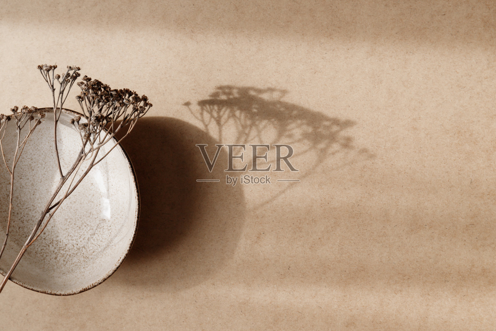 极简的陶瓷碗与干燥的植物在牛皮纸背景。复制空间，平铺。照片摄影图片