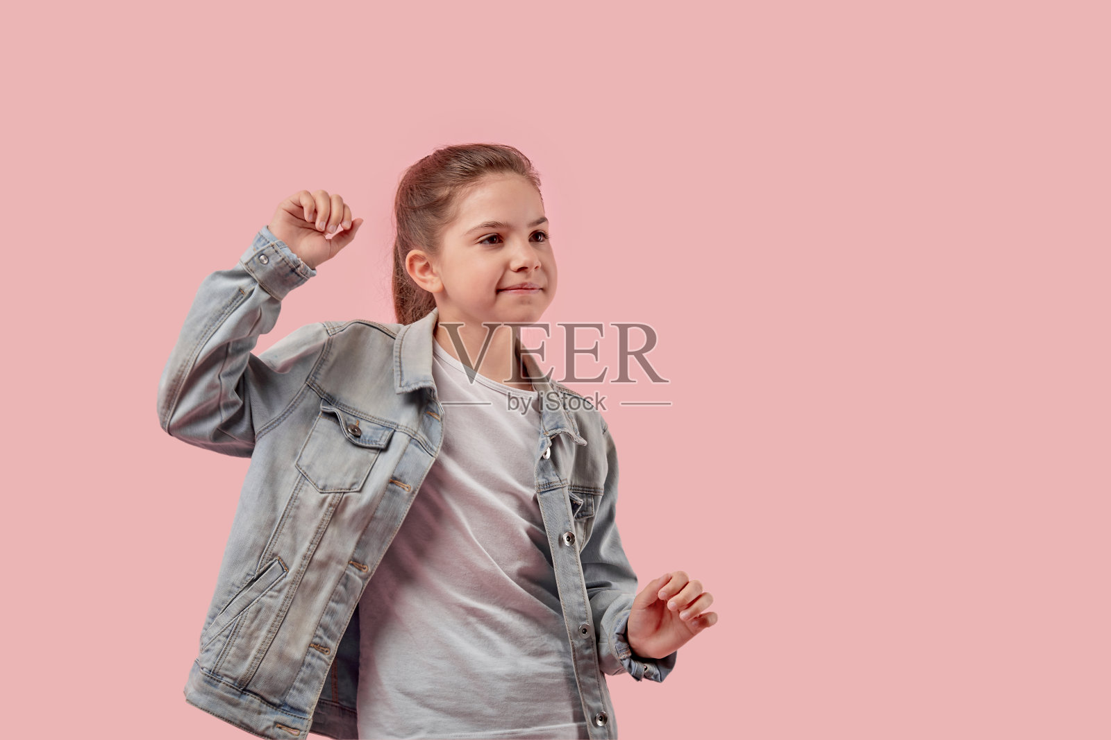 美丽的女孩穿着时髦的衣服跳舞。牛仔夹克和白色背心。照片摄影图片