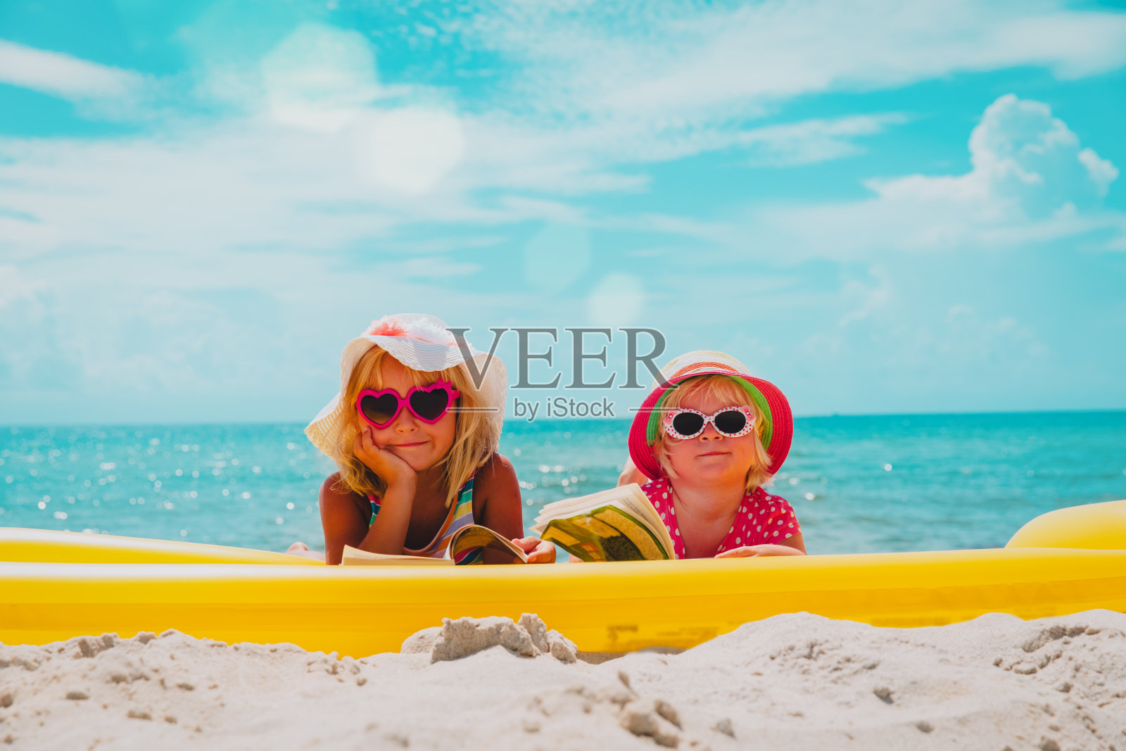 小女孩们在沙滩上看书，和家人一起度假照片摄影图片