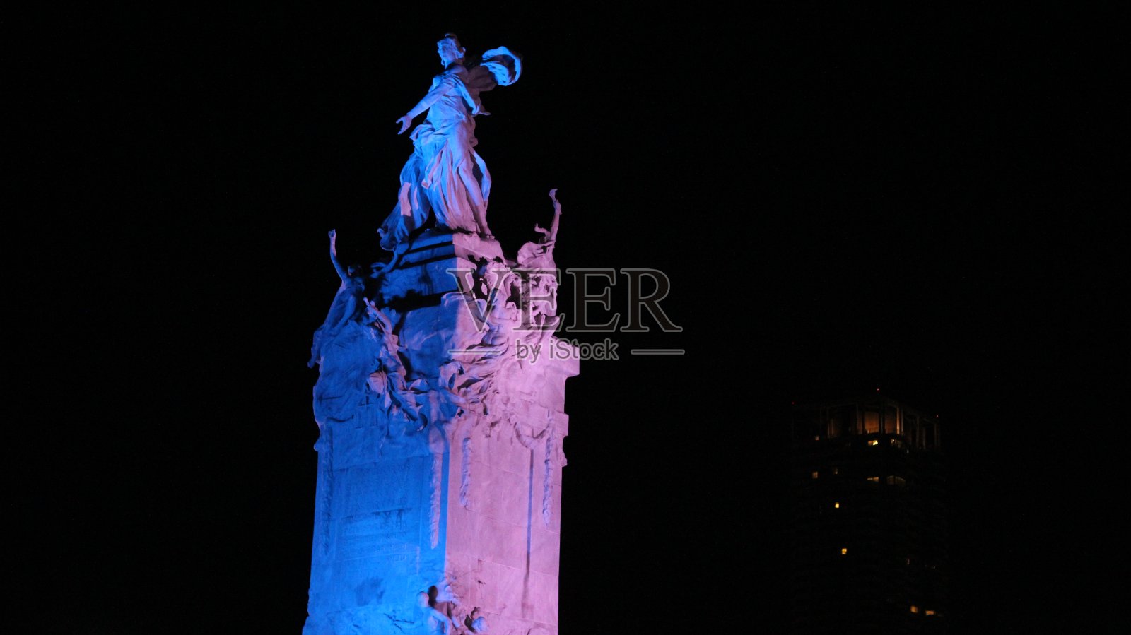 一个古老的白色大理石纪念碑的顶部，被蓝色和绿松石灯照亮，在巴勒莫社区，布宜诺斯艾利斯照片摄影图片