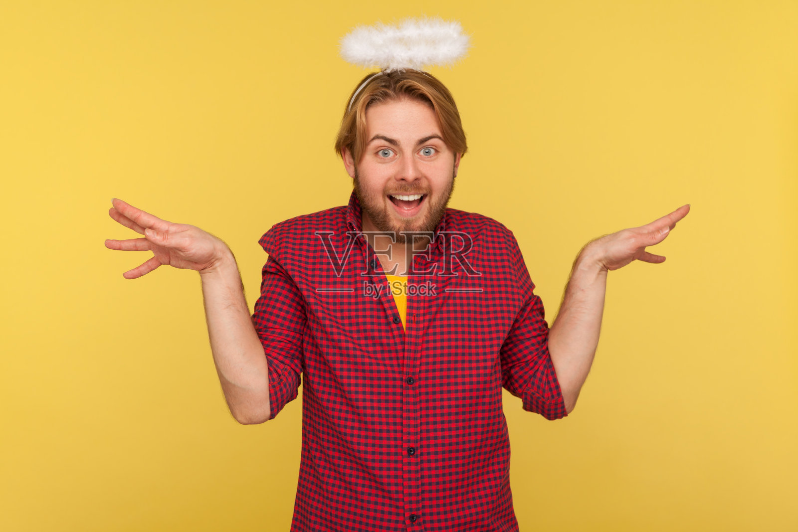 一个滑稽的长着胡子的家伙，头上顶着圣光，把双手举得像飞翔的翅膀，假装天使，看着相机照片摄影图片