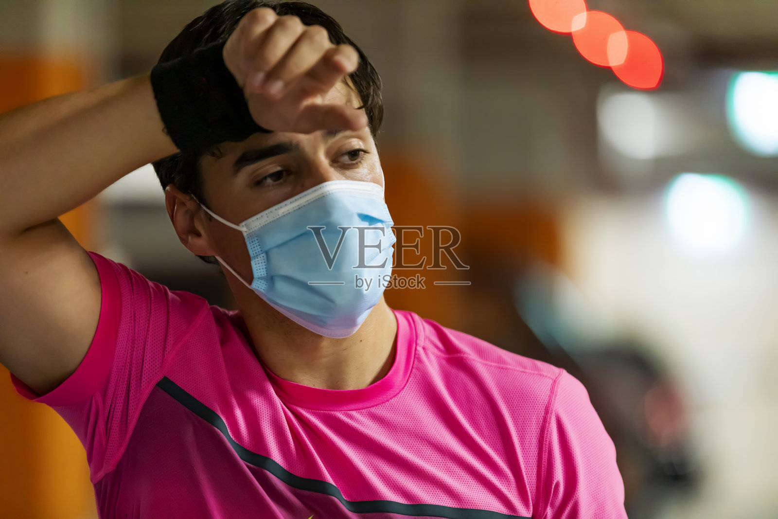 戴着面具练习很困难。年轻的运动员在短跑后休息。新型冠状病毒肺炎照片摄影图片