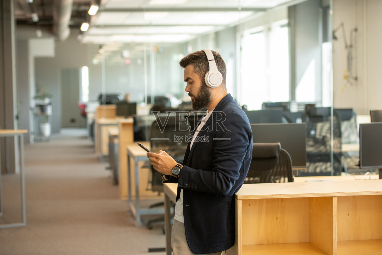 当代严肃的年轻白领，在智能手机上滚动耳机照片摄影图片
