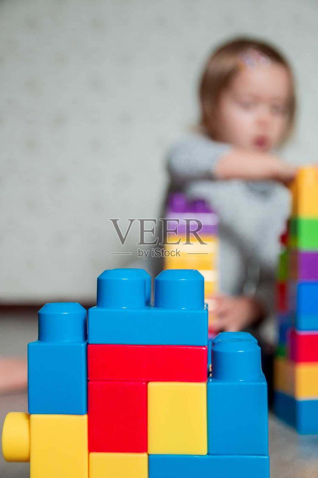明亮的塑料积木背景上有一个无法辨认的小女孩。发展的玩具。早期的学习。照片摄影图片