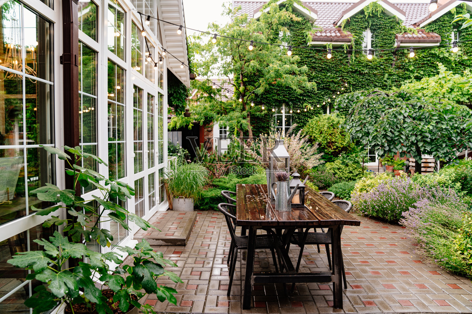 夏日雨中，院子里的桌上摆着一束干花和蜡烛。照片摄影图片