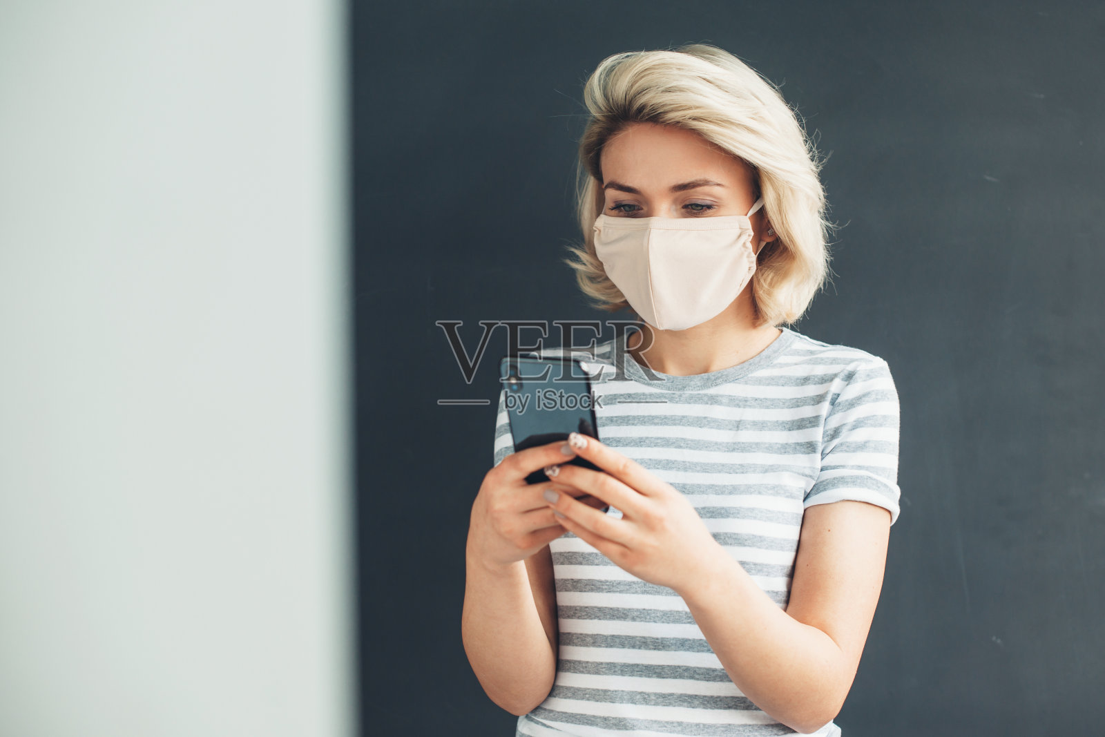 金发白种女人戴着面具在家用手机聊天照片摄影图片