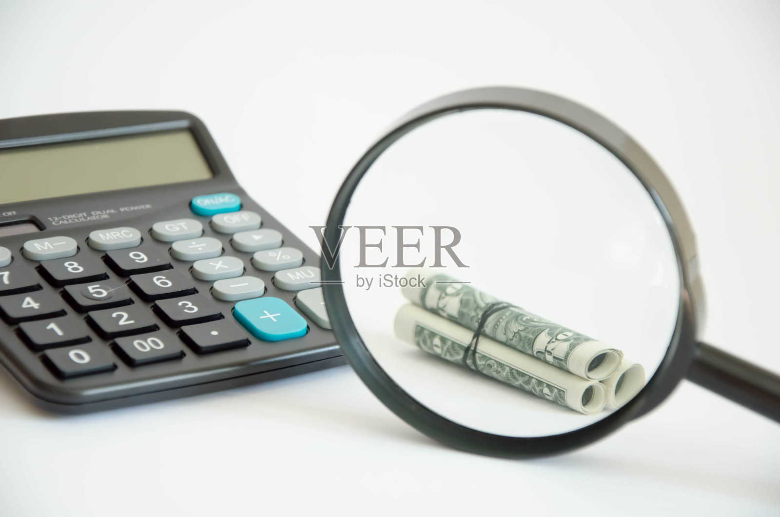 通过放大镜增加金钱。在后台是一个计算器照片摄影图片