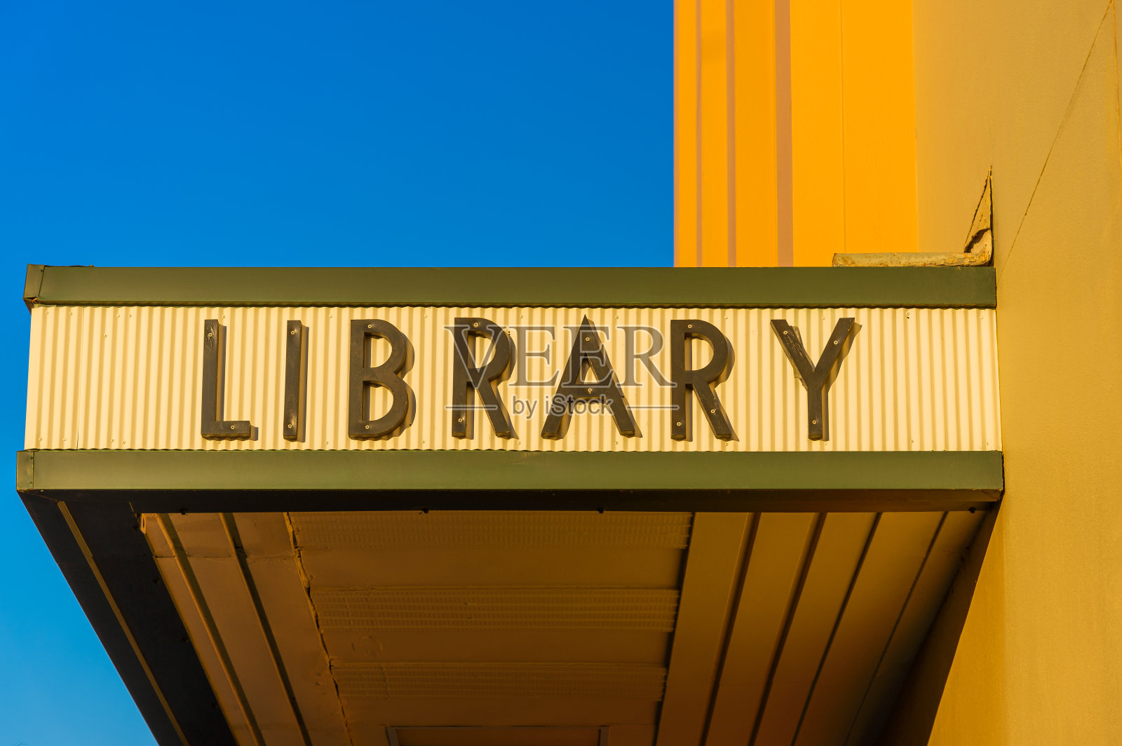黄色波纹铁皮帐篷上的绿色字体的公共图书馆标志照片摄影图片