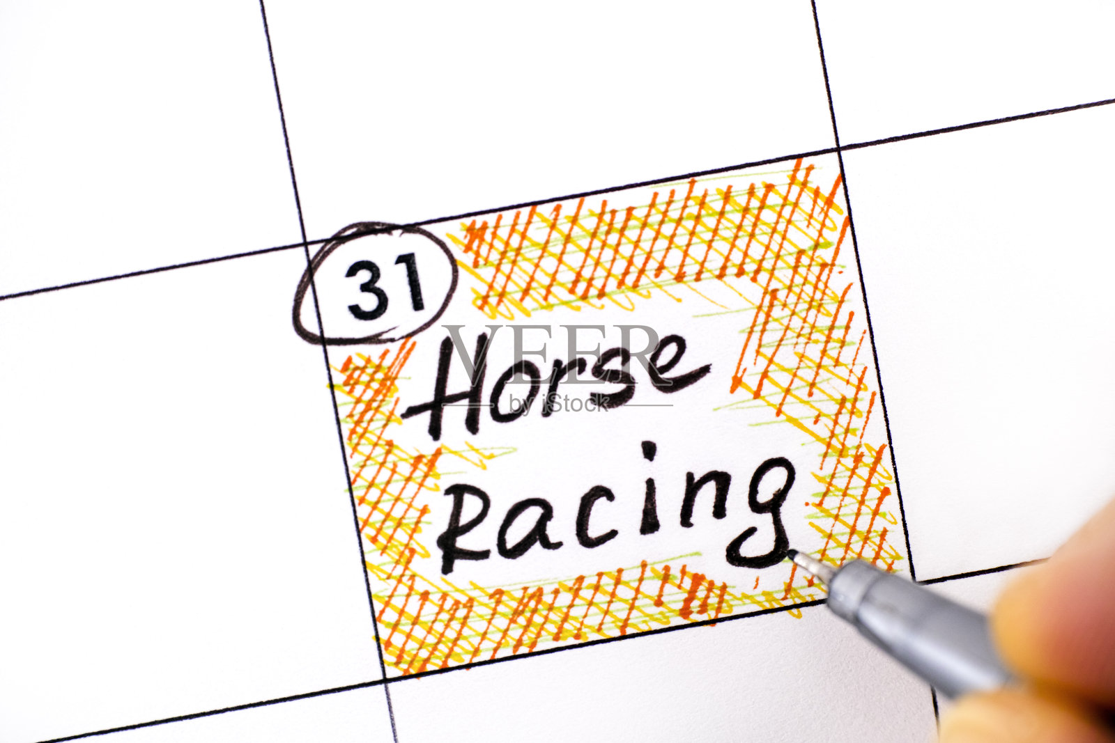 女人用手指用笔在日历上书写赛马提醒。照片摄影图片