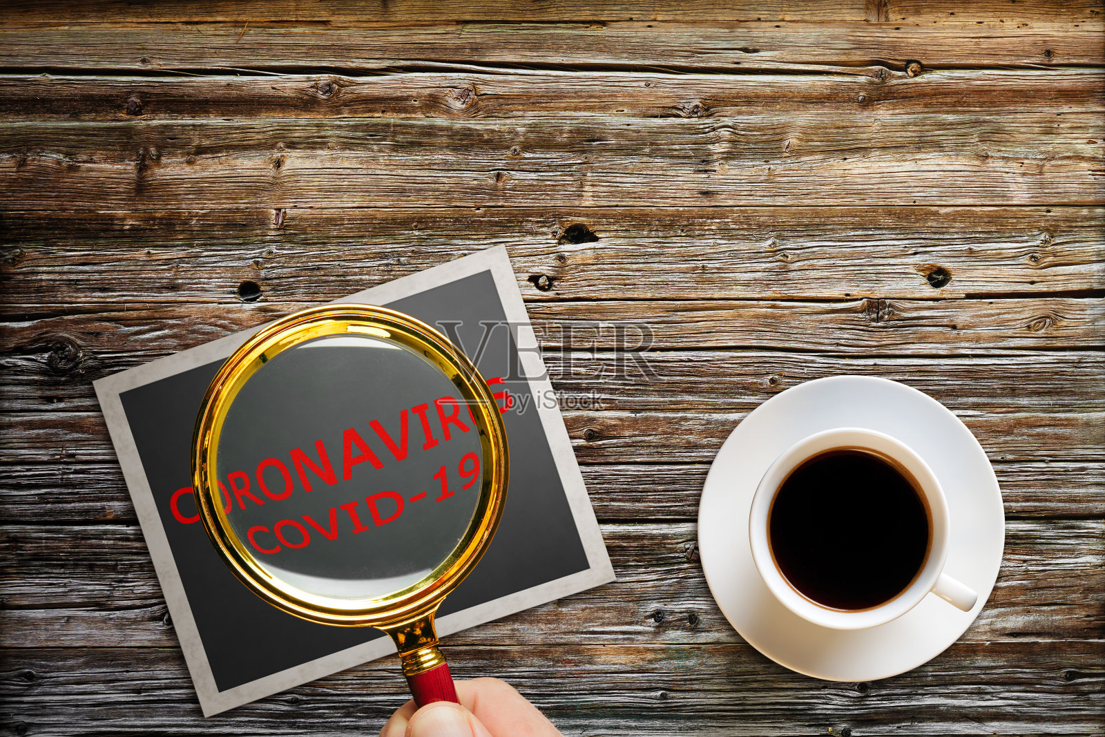 一名男子手持放大镜在一张照片卡上，以灰色木材为背景的冠状病毒和空气污染pm2.5概念。新型冠状病毒肺炎照片摄影图片