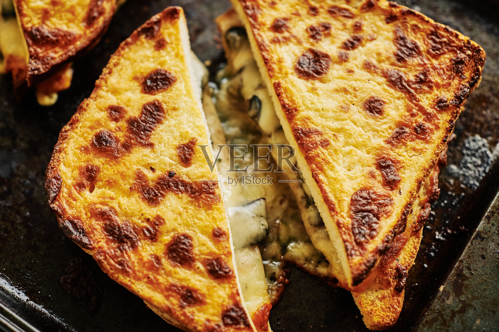 刚出炉的奶酪蘑菇三明治放在一个旧烤盘上。照片摄影图片