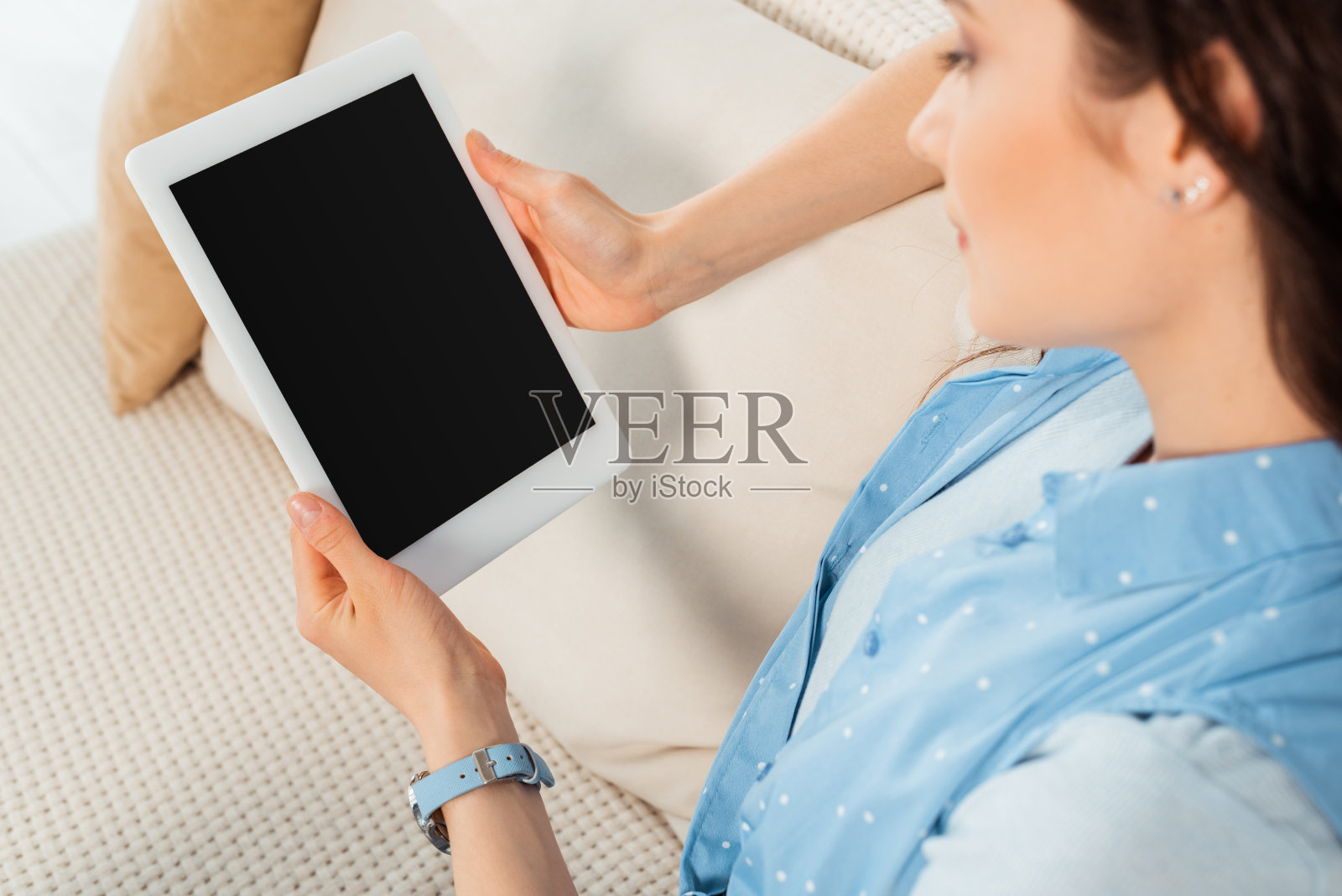 年轻女子在沙发上手持空白屏幕的平板电脑照片摄影图片