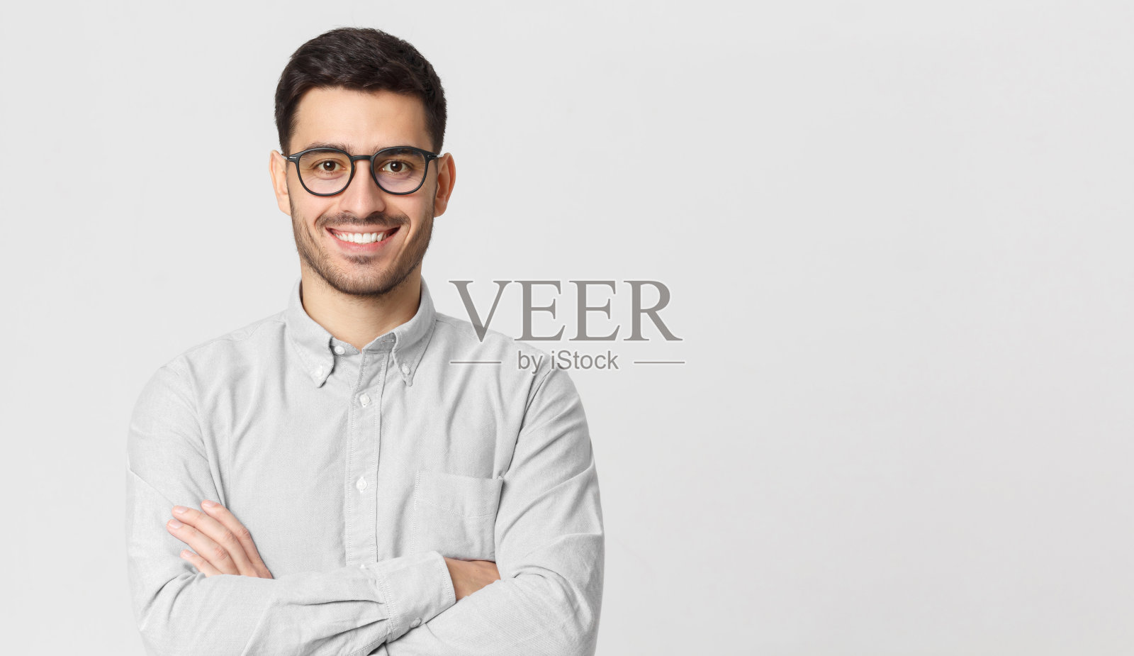 一个身穿灰色衬衫，戴着眼镜的商人，双臂交叉站着，微笑着，充满自信，与右边的文案空间隔离照片摄影图片