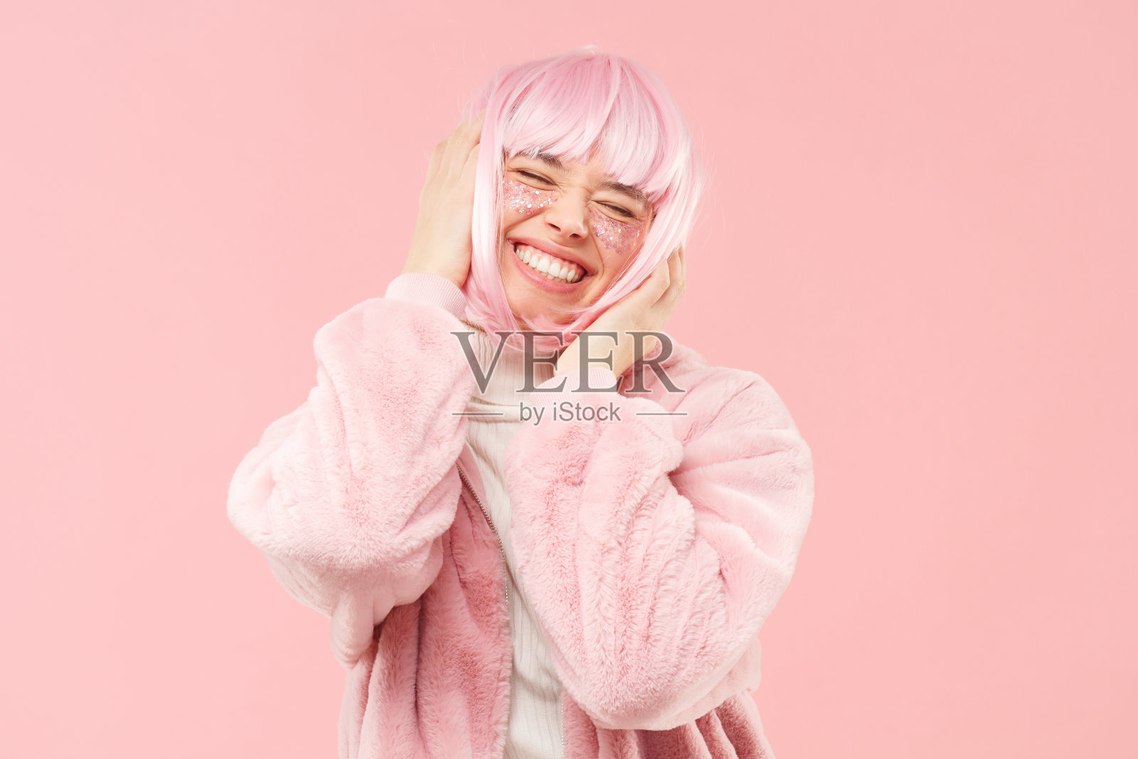 年轻的笑着快乐的女孩，皮草和粉红色的头发，触摸她的头和舞蹈音乐闭眼孤立照片摄影图片