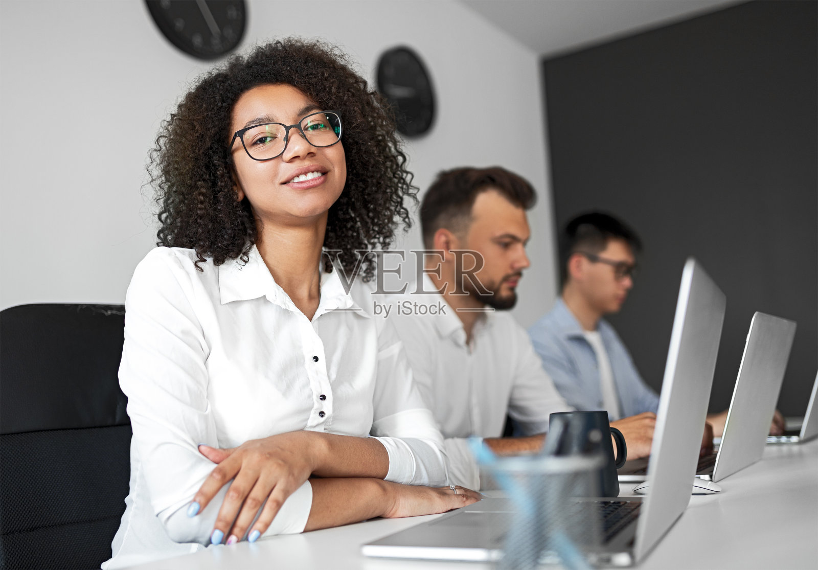 一个积极忙碌的女人，在办公室用笔记本电脑工作，看着摄像头照片摄影图片