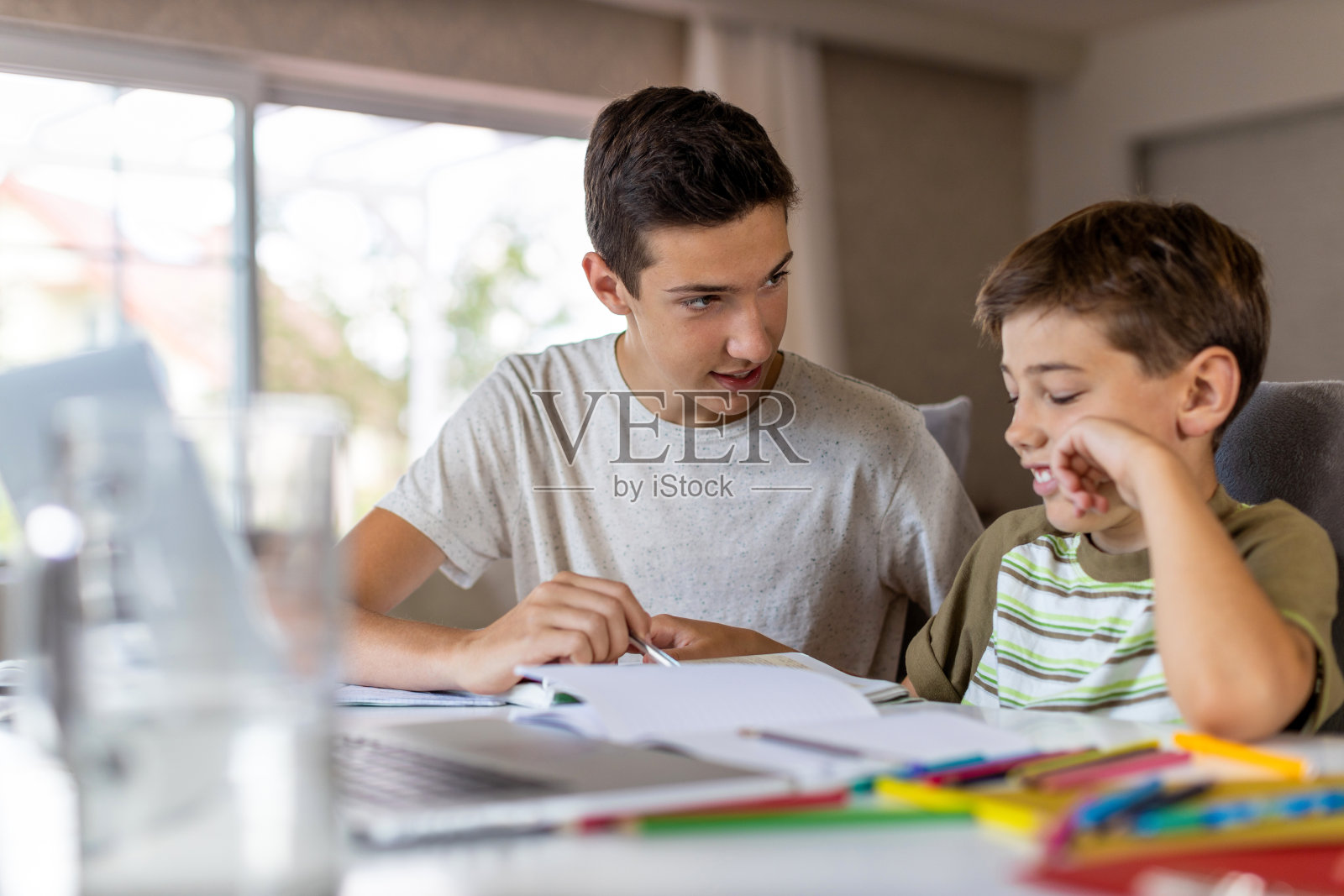 一个十几岁的男孩在家里帮助他的弟弟做作业照片摄影图片