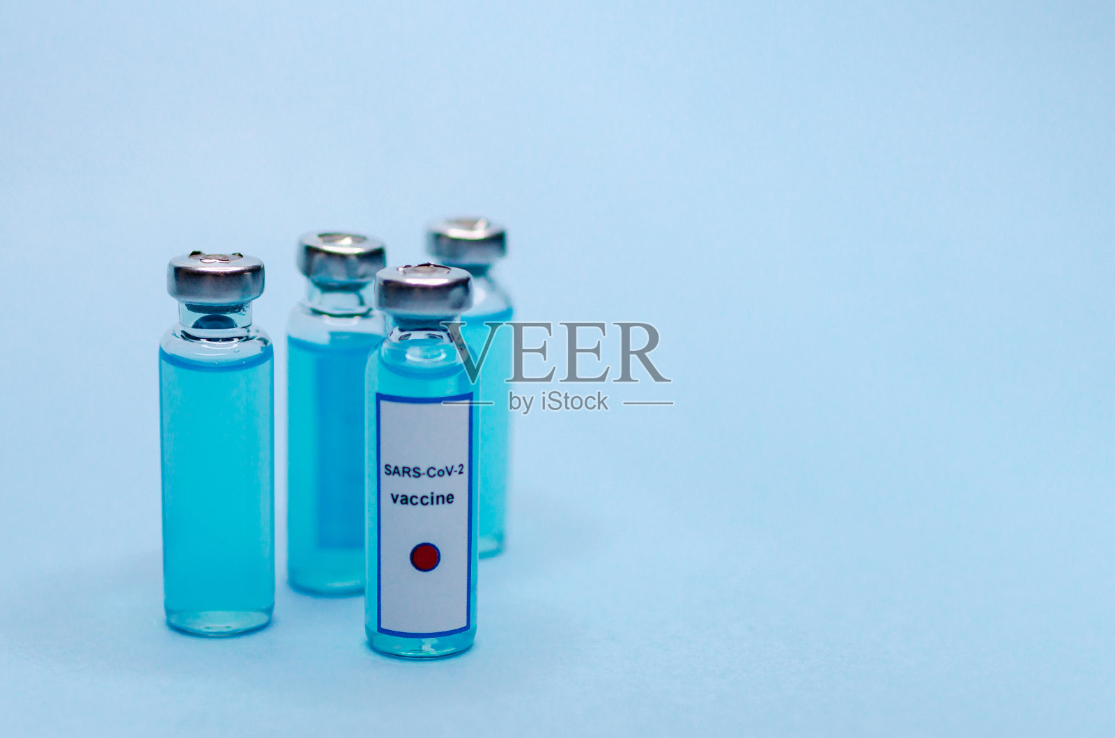 蓝色背景的玻璃瓶冠状病毒疫苗。照片摄影图片
