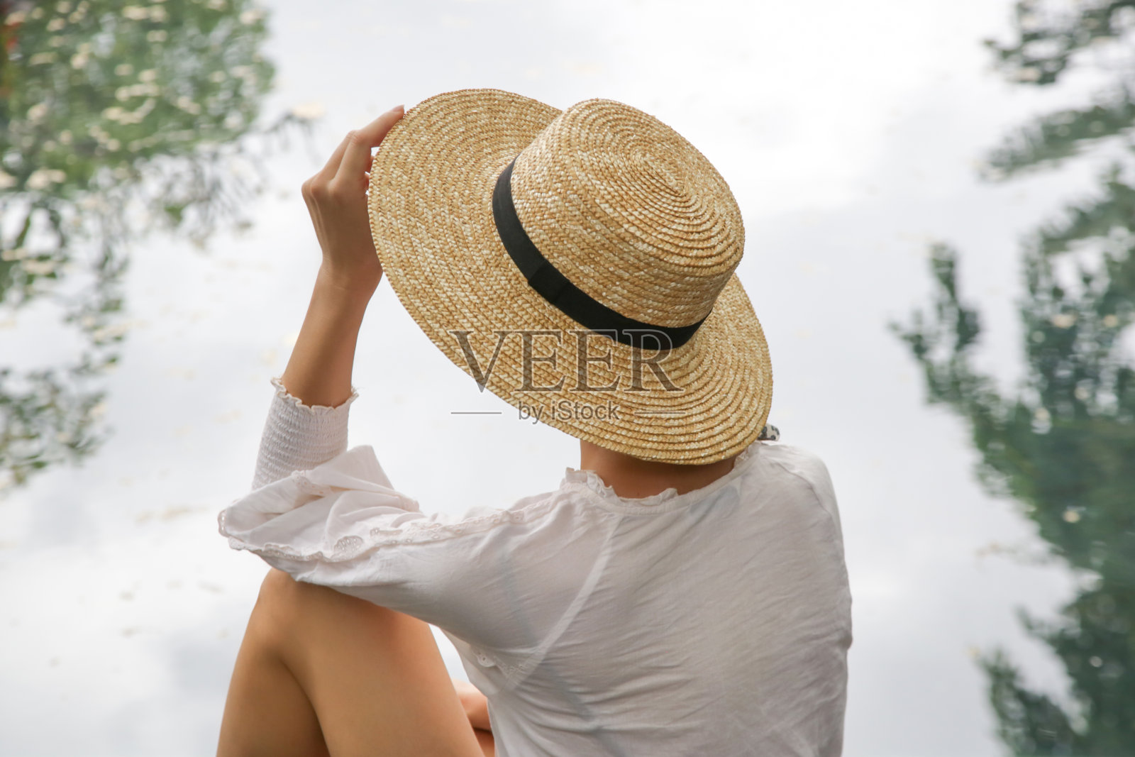 背景的女人戴着草帽和看向水照片摄影图片