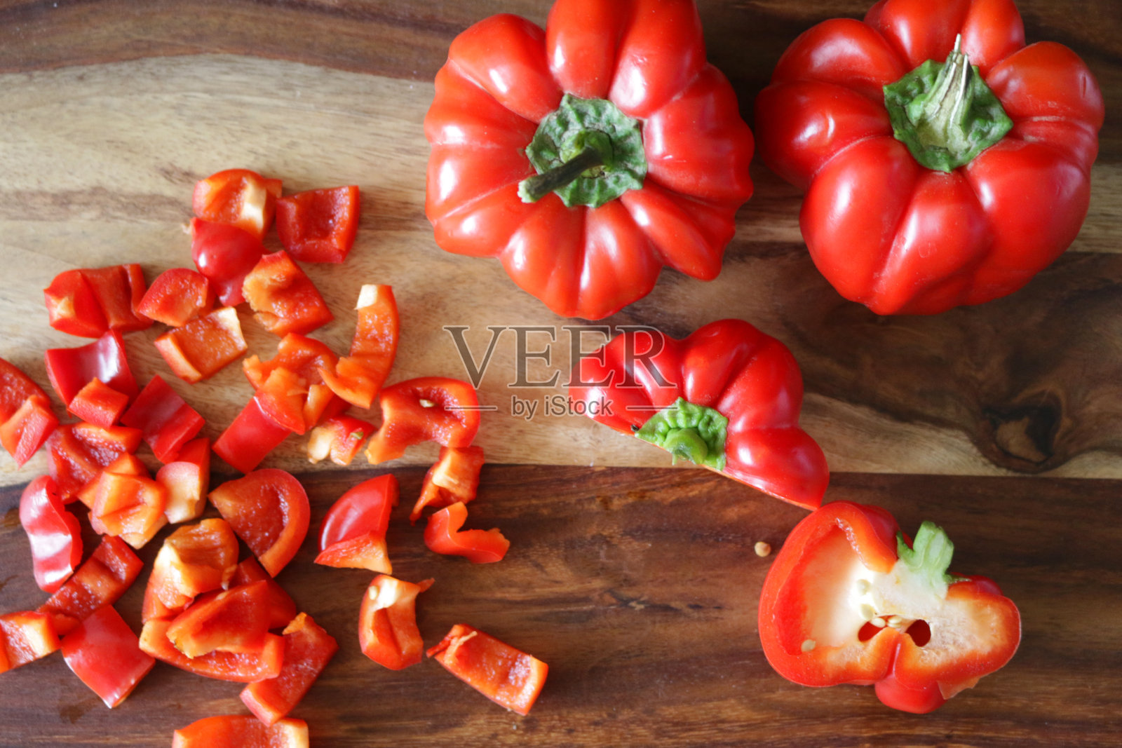 红甜椒在木砧板上整片切成两半和小块的形象，俯瞰高处照片摄影图片