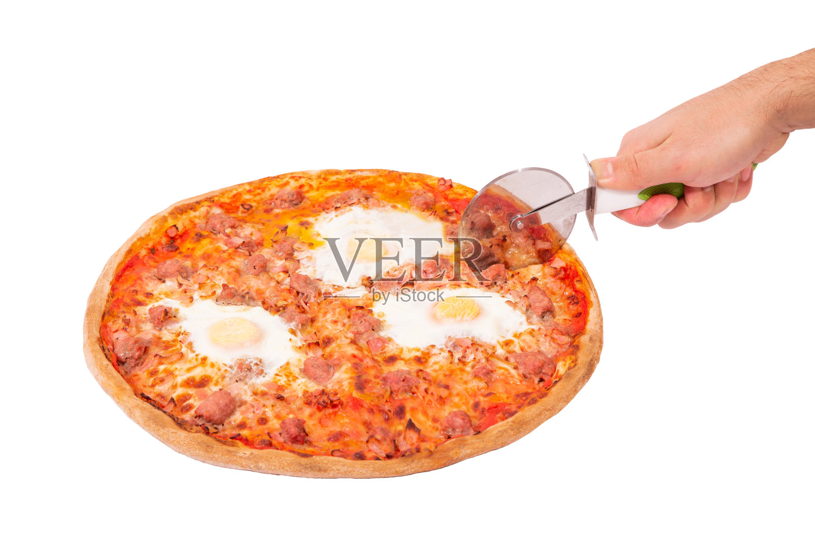 美味的披萨配牛肉香肠，鸡蛋和培根或早午餐披萨。男子的手用披萨切割器将披萨隔离在白色背景上，角度视图照片摄影图片