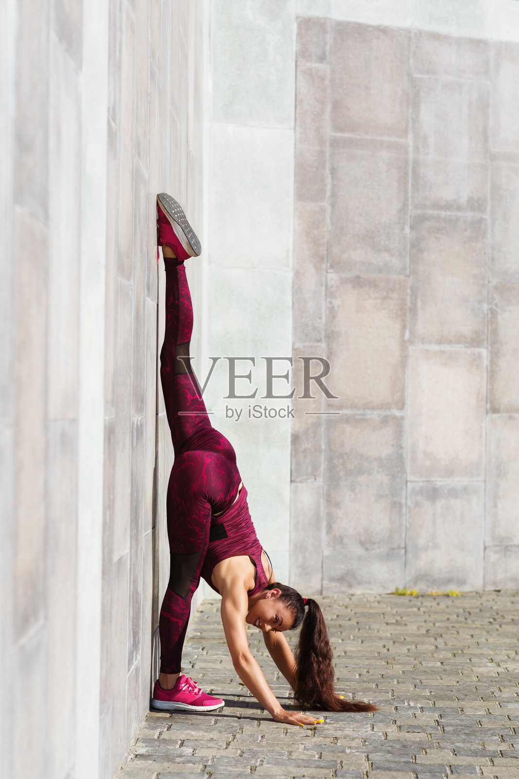 女运动员在新鲜的空气中靠在墙上做体操。以运动和健康生活为主题的理念照片摄影图片