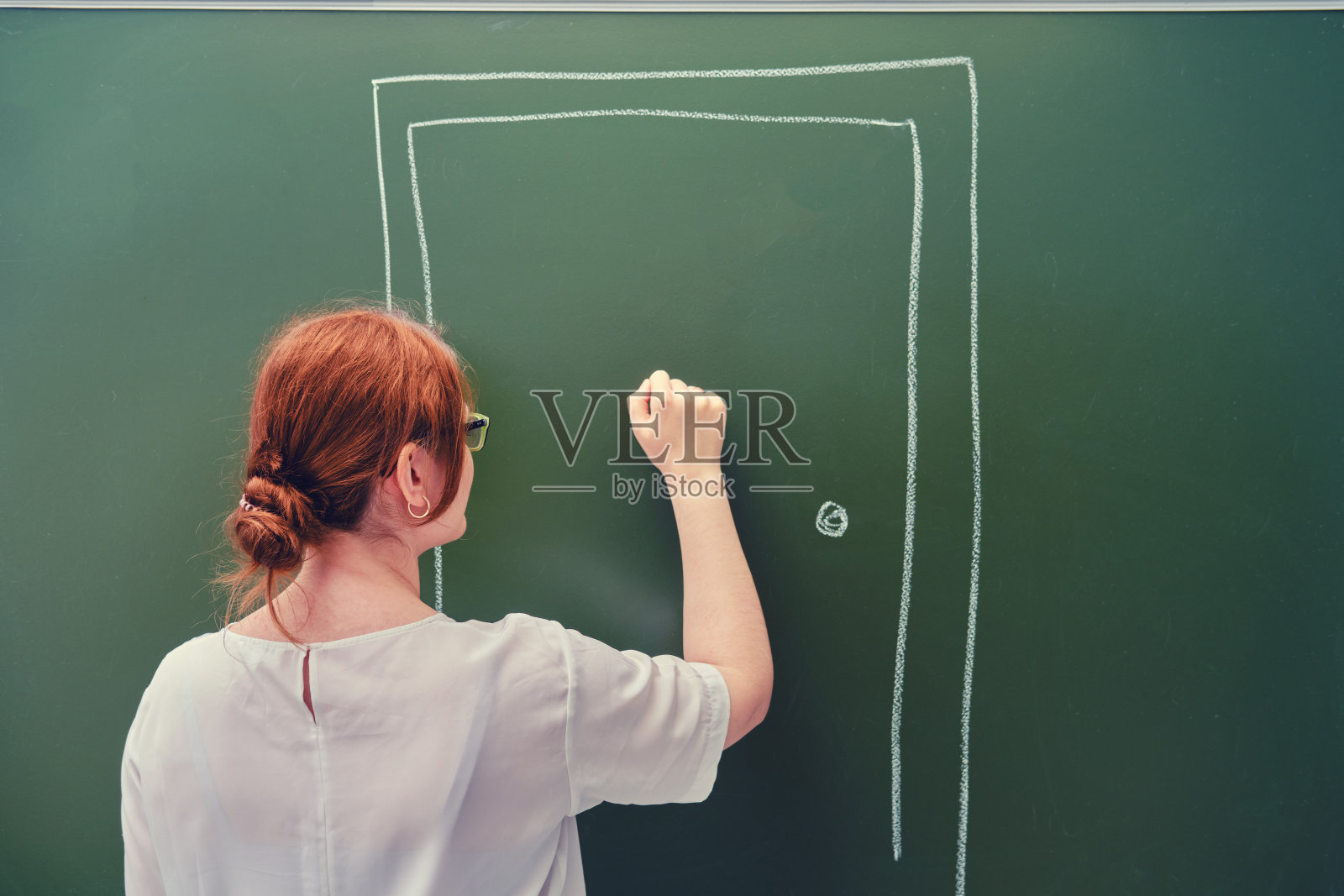 女老师敲着黑板上用粉笔画的门。学校在线教育的概念照片摄影图片