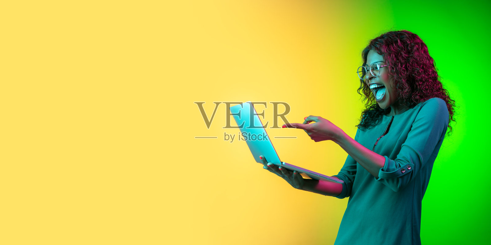 非裔美国年轻女子的肖像在霓虹灯的黄绿色渐变背景上被孤立照片摄影图片