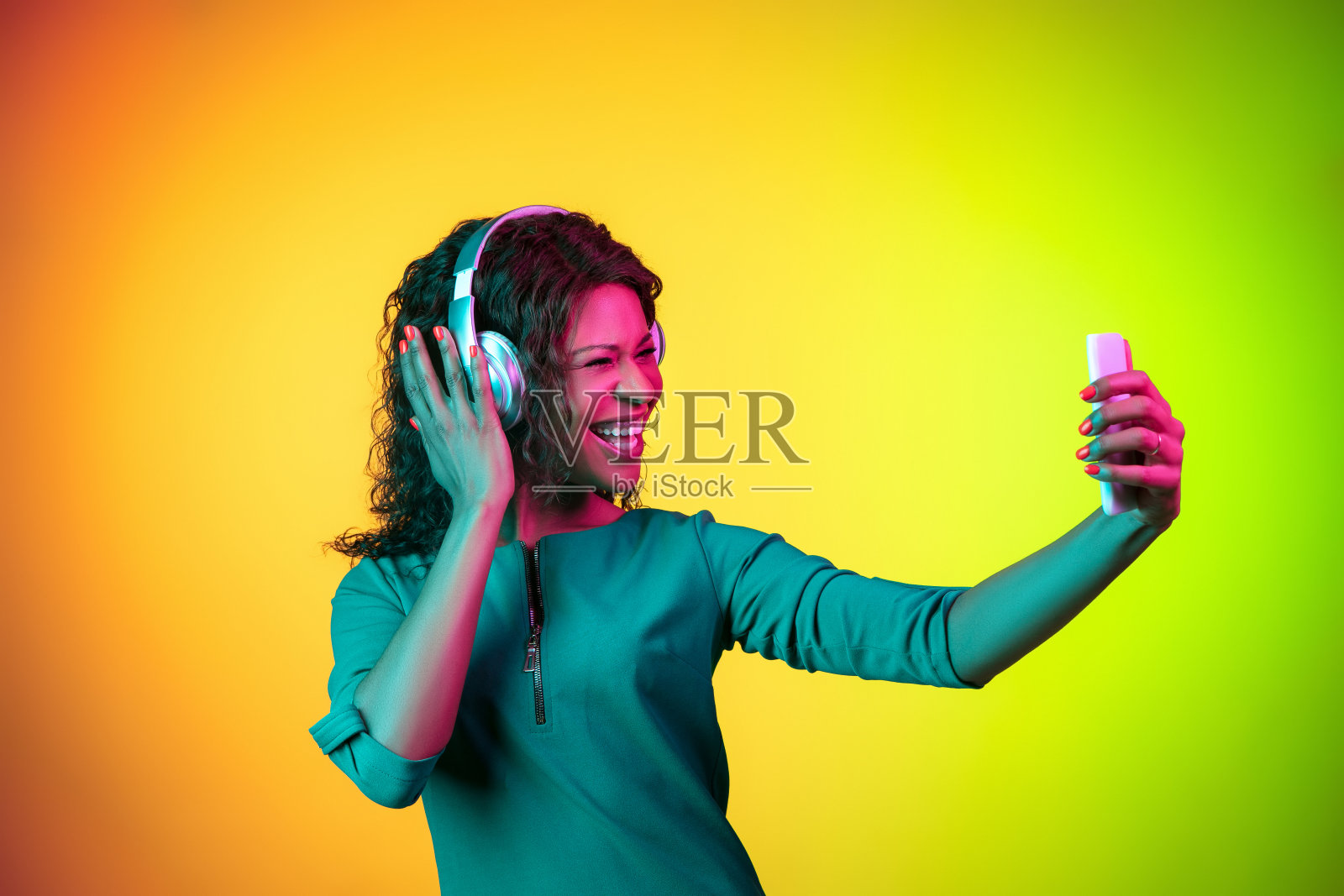 非裔美国年轻女子的肖像在霓虹灯的黄绿色渐变背景上被孤立照片摄影图片