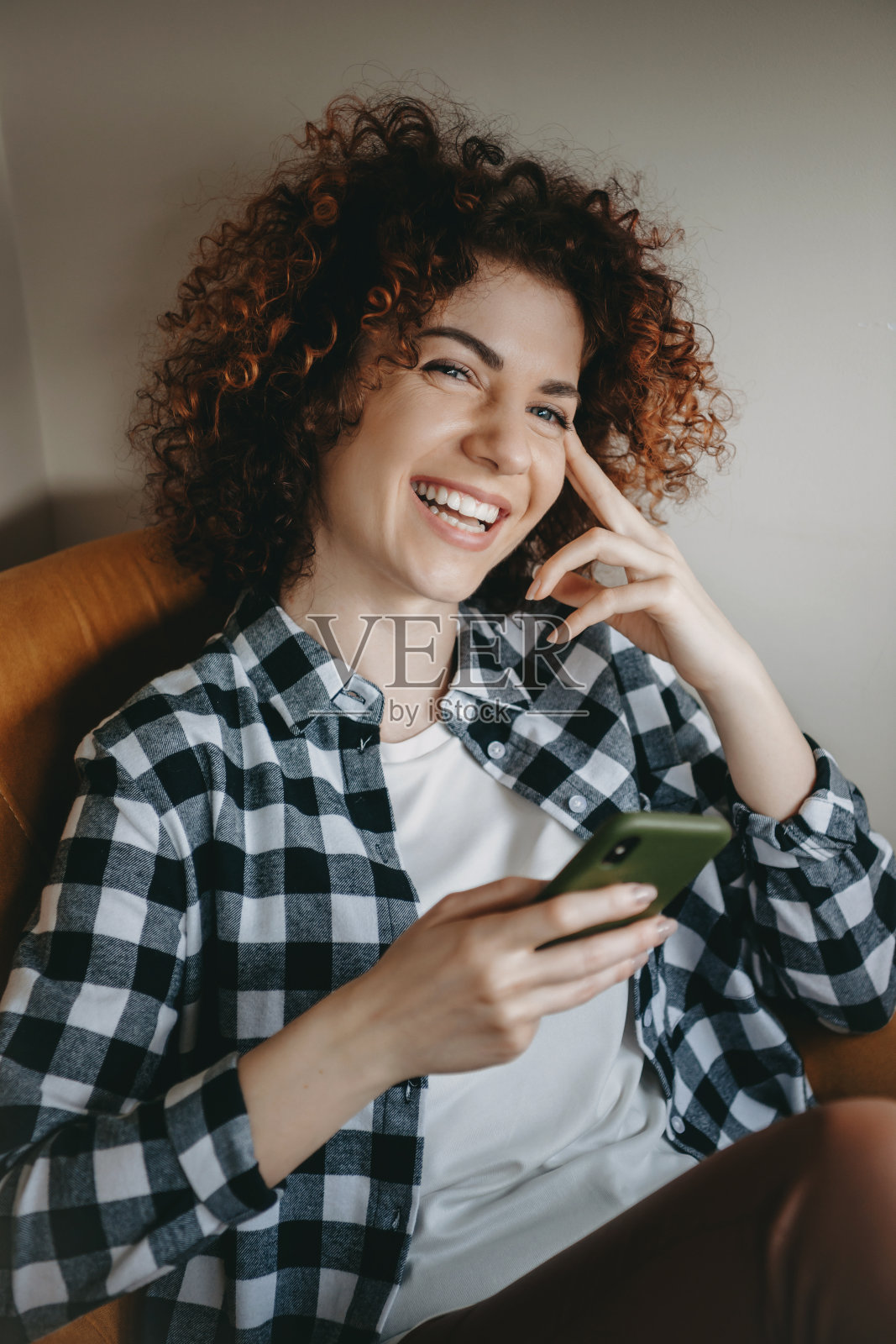 可爱的白人女人与卷发微笑着坐在沙发上聊天的手机照片摄影图片