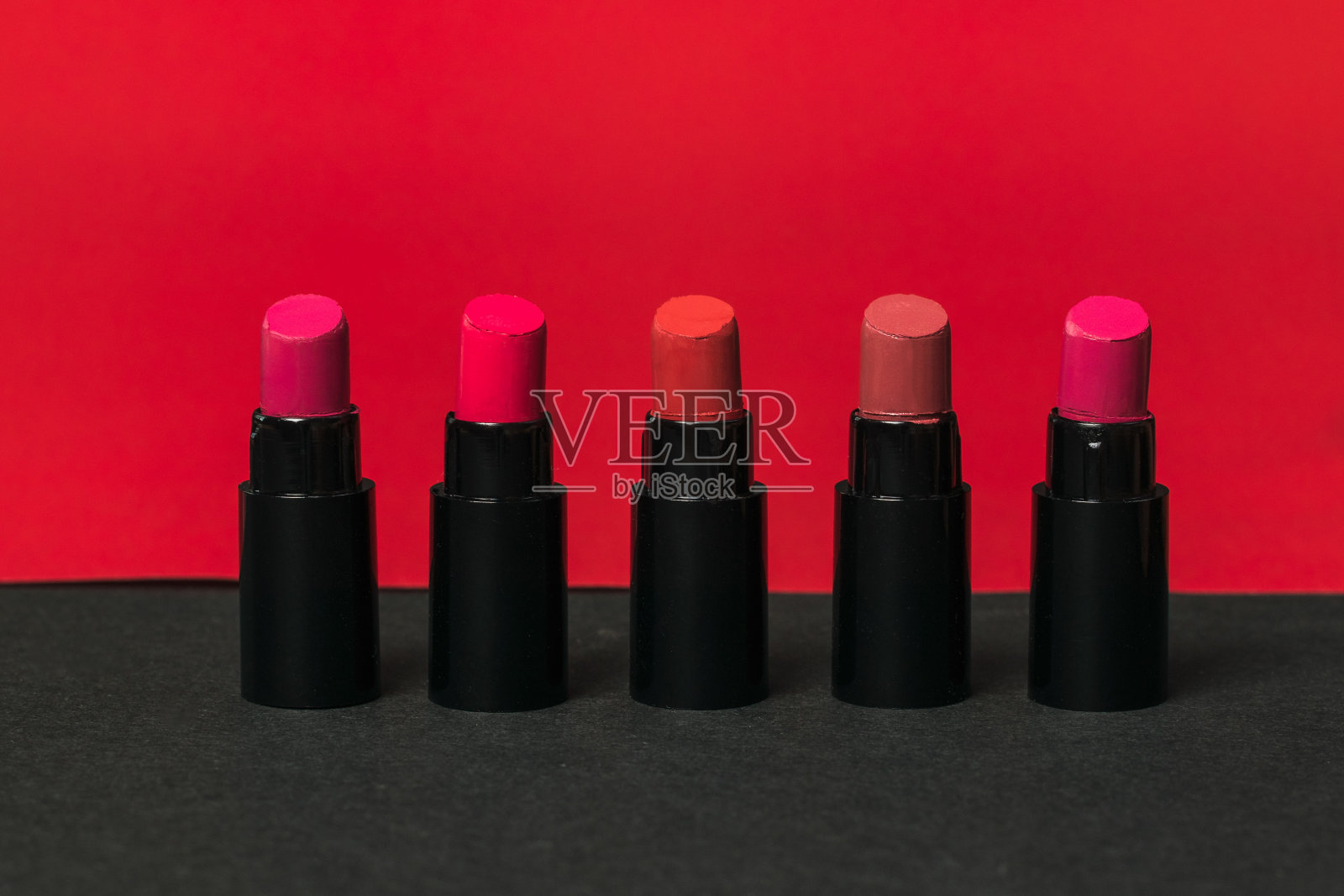 五瓶红黑底色的口红。照片摄影图片