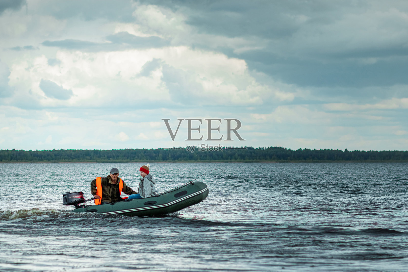 祖父和孙子在湖上乘坐摩托艇。家庭的概念，暑假，一代。副本的空间。照片摄影图片