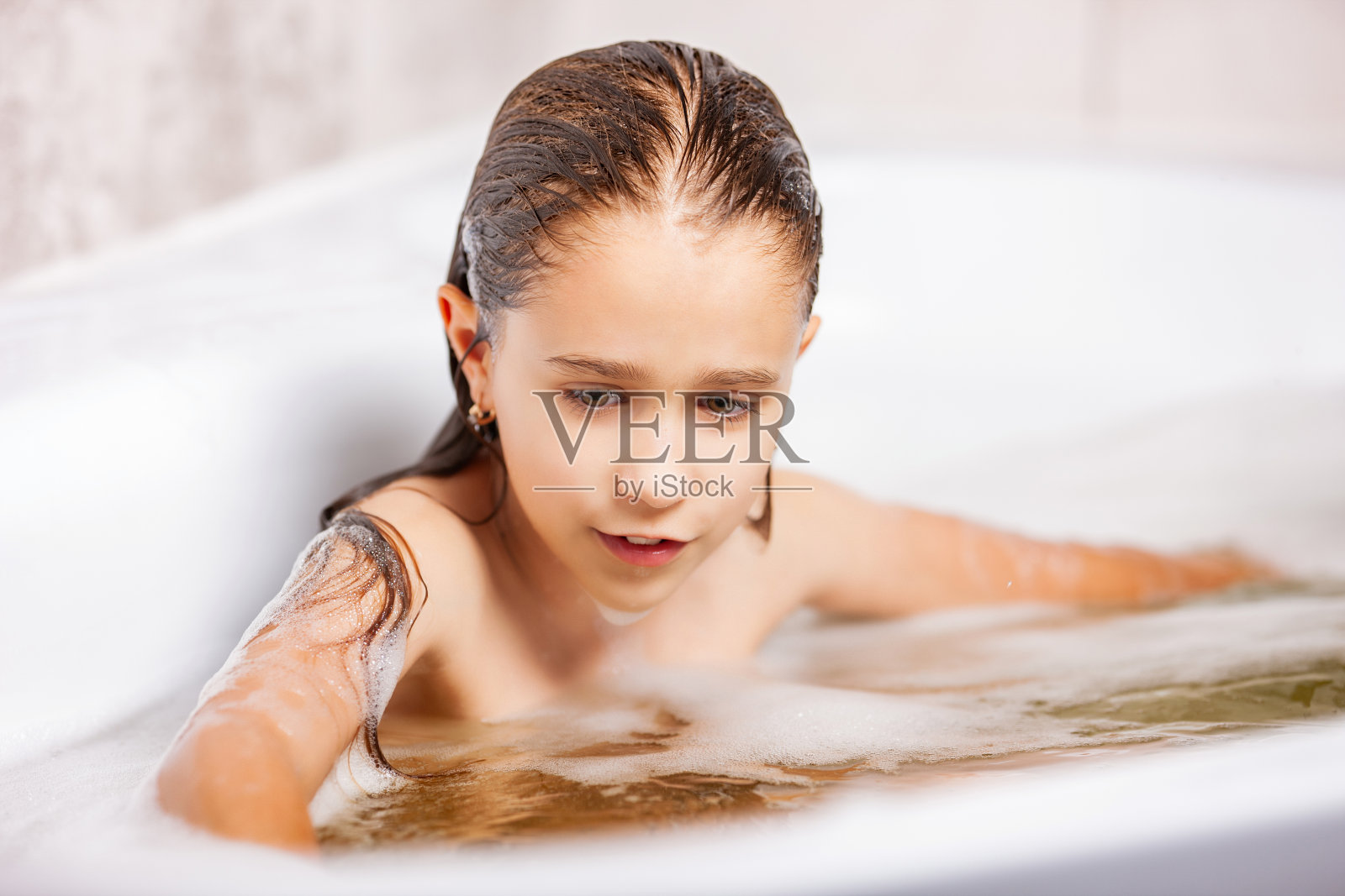 一个可爱的白人小女孩在浴缸里泡澡，在隔离期间玩得很开心照片摄影图片